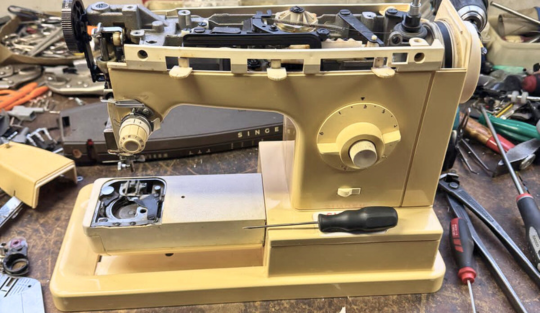 Macchina da cucire smontata sul banco di lavoro per una revisione